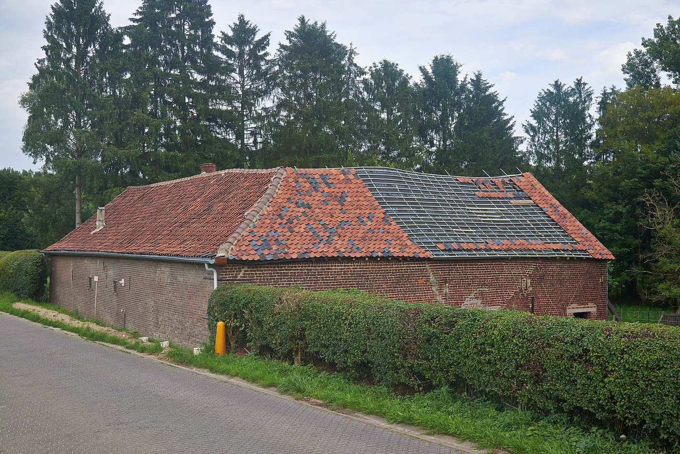 Deels afgedekt boerderijdak waar de panlatten zichtbaar zijn tijdens een herstelling